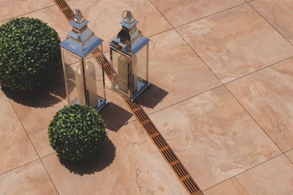 ACO Threshold Drain with a CorTen grating on a patio with lanterns and planters